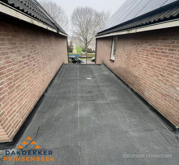 Plat dak met bitumen dakbedekking tussen bakstenen muren in Prinsenbeek Plat dak met bitumen dakbedekking tussen bakstenen muren in Prinsenbeek