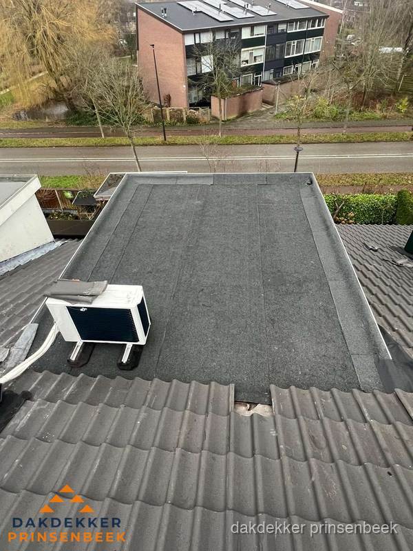 Plat dak inspectie met bitumen bedekking naast schuin pannendak in Prinsenbeek