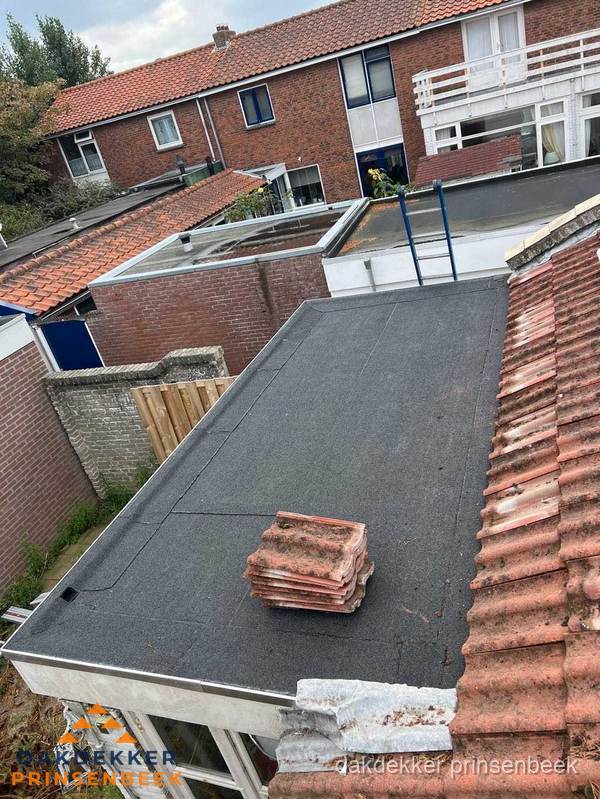 Plat dak aanbouw met bitumen naast schuin pannendak in Prinsenbeek