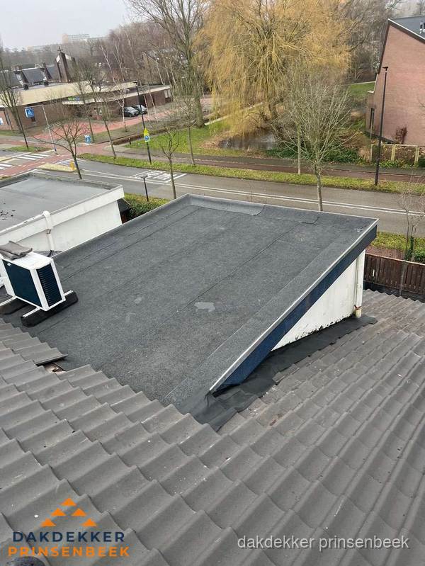 Plat dak met bitumen dakbedekking naast schuin pannendak in Prinsenbeek