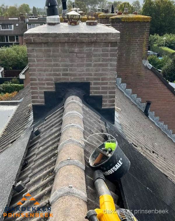 Schoorsteen met loodaansluiting en nokvorst op pannendak in Prinsenbeek