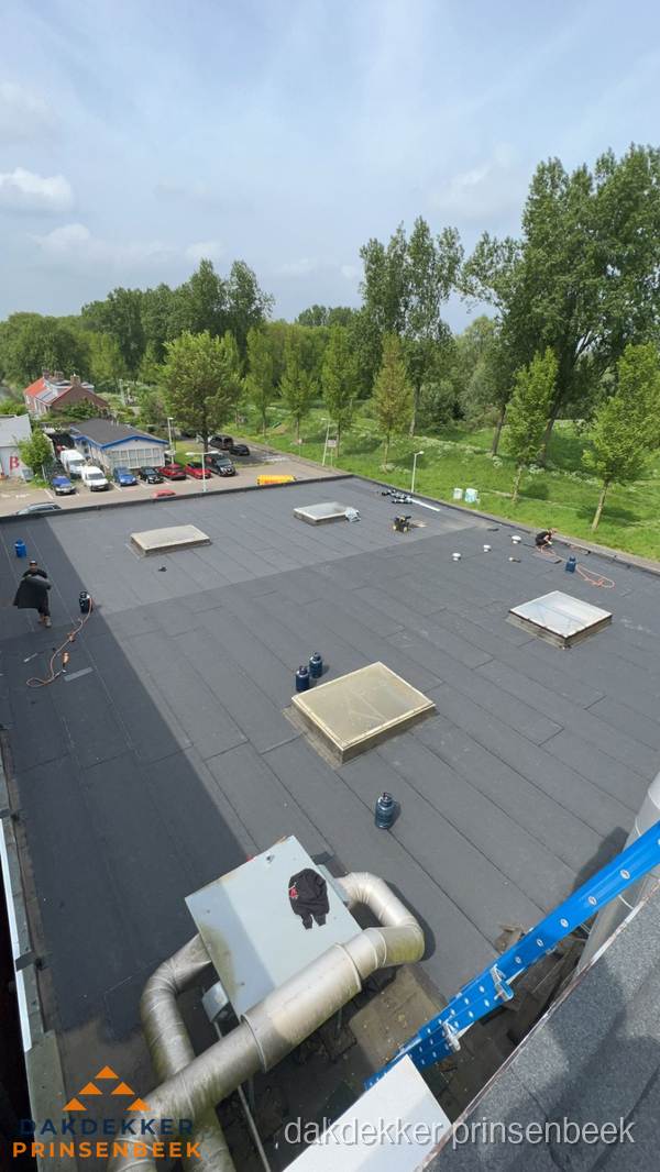 Dakdekker aan het werk op groot plat dak met bitumen in Prinsenbeek