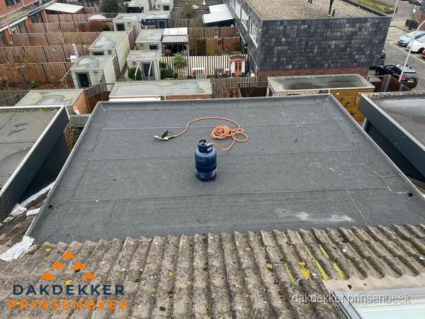 Plat dak met nieuwe bitumen dakbedekking en brandgereedschap in Prinsenbeek