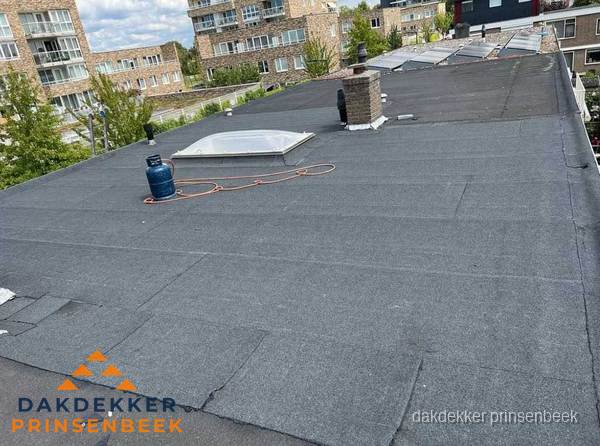 Bitumen dakbedekking op plat dak met lichtkoepel en schoorsteen in Prinsenbeek